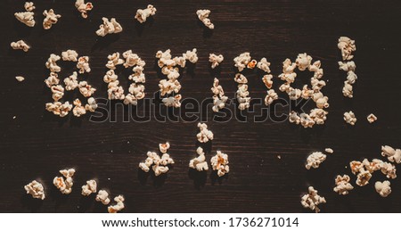 The Phrase " Boring!" laid out of popcorn on a wooden table