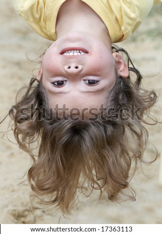 a picture of a cute young little girl hanging upside-down