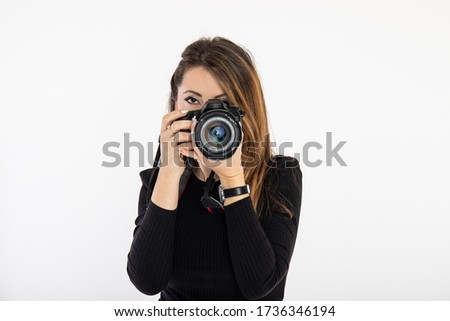 Woman photographer looking through the lens in studio. Isolated on white background.