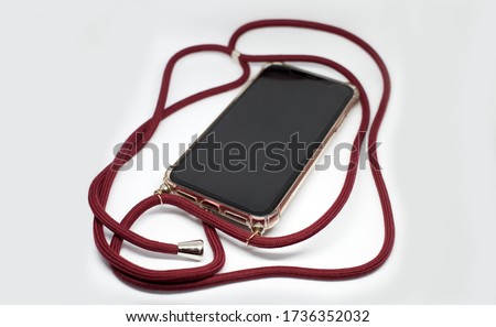 Smartphone in transparent case crossbody with red long textile strap, comfortable usage of mobile phone protective accessory Royalty-Free Stock Photo #1736352032