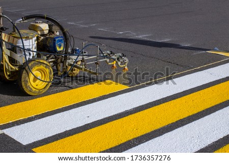 Road workers use hot-melt scribing machines to painting pedestrian crosswalk on asphalt road surface in the city. Royalty-Free Stock Photo #1736357276