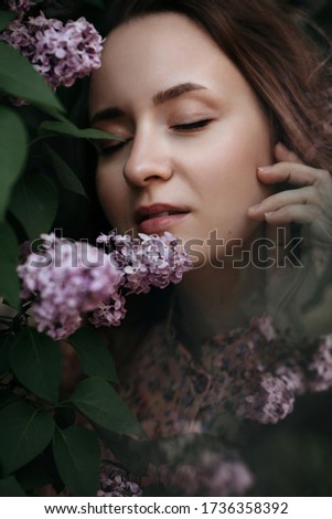 Soft focus portrait of young girl near lilac