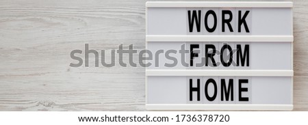 'Work from Home' words on a lightbox on a white wooden surface, top view. Overhead, from above, flat lay. Space for text.