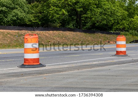 Two orange and white traffic barrels dividing a rural street in a road construction zone, copy space, horizontal aspect