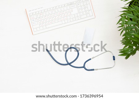 Keyboard, phone and stethoscope on a wooden background. The view from the top. Doctor's workplace
