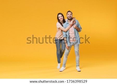 Funny young couple two friends guy girl in pastel blue casual clothes posing isolated on yellow wall background studio portrait. People lifestyle concept. Mock up copy space. Hugging, looking camera