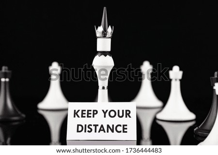 Concept chess pieces express social distancing with white board and text, keep your distance, in front of the center piece on the chess board.
