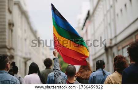 Rear view of people in the pride parade. Group of people on the city street with gay rainbow flag. Royalty-Free Stock Photo #1736459822