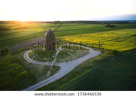Beautiful sunset above the old windmill on the field. Old mill in Poland photographed from the air, drone photography, aerial view. Rapeseed field in the background.