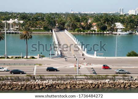 The aerial view of cars passing by the bridge-entrance to artificial Palm Island, the luxury residential district in Miami (Florida).