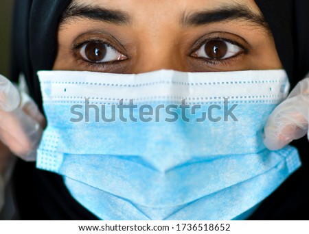 A arab Muslim woman wearing masks and gloves outside house. The woman is protecting herself from coronavirus and other airborne particles and diseases.COVID-19 Royalty-Free Stock Photo #1736518652