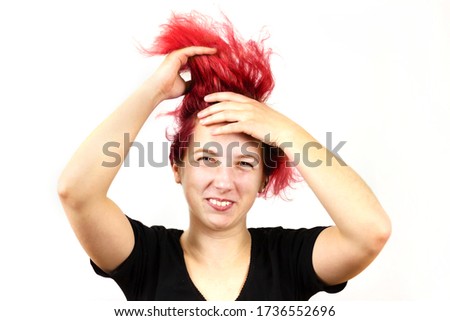 Close-up of a smiling girl with red hair doing a rocker Mohawk on her head, on a white background. Informal teenagers, concept.
