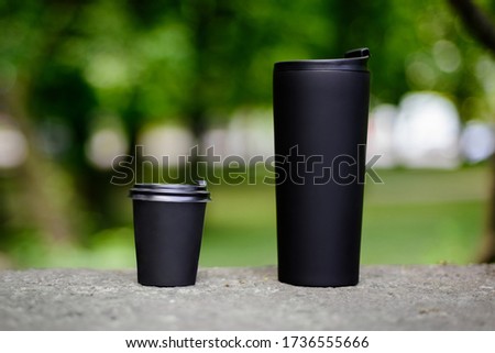 Comparing thermo cup with disposable paper coffee cup over green background