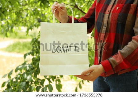 Woman holding paper bag with text Donate outdoor