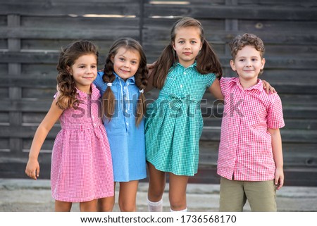 Cheerful children boy and three girls in clothes with a picture in a cage rest on the street