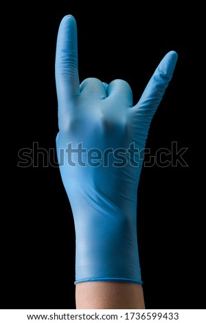 Doctor's hand in medical gloves showing devil horns gesture isolated on black background with clipping path. Concept of protection against pandemic and viruses.