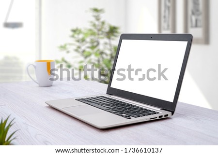Laptop computer mockup. Home work desk with coffee mug beside. Plant in background