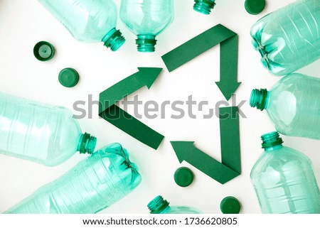 Green paper recycling symbol with empty plastic water bottles