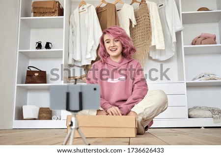 Happy hipster gen z teen girl fashion social media channel blogger with pink hair wear hoodie recording unboxing vlog on phone video camera tutorial sit on floor with online store clothes order box. Royalty-Free Stock Photo #1736626433