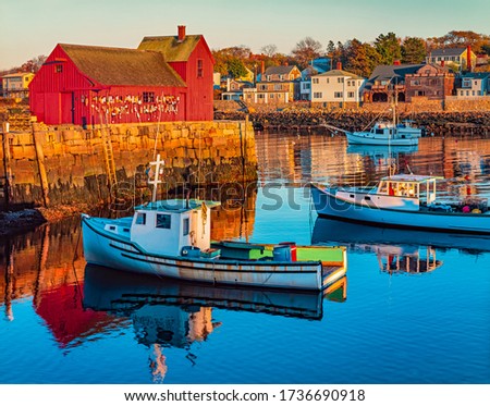 Rockport Harbor in Massachusetts with it's lobster boats  and village reflect in the still water of the day. The colors give the town a nostalgic feeling. 