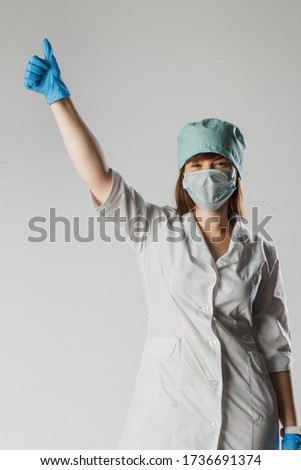 Young woman nurse on isolated background showing gesture approvals showing thumb up symbol and shape with hands. Medical concept.