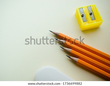 Four pencils and an eraser on a light background