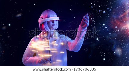 Beautiful woman with purple hair in futuristic costume over dark background. Girl in glasses of virtual reality. Augmented reality game, future technology, AI concept. VR. Neon light.