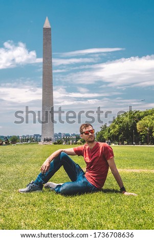 Young guy exploring Washington city near Washington monument on sunny day with blue sky background.