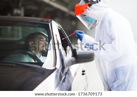 COVID-19 drive-thru rt-PCR detection site,medical worker performing nasal swab specimen collection on young male driver,free Coronavirus public diagnostic procedure,mobile car testing center clinic Royalty-Free Stock Photo #1736709173