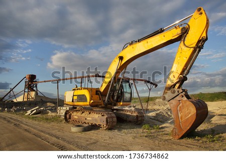Crawler excavator next to the water supply system in the sand pit against the blue sky