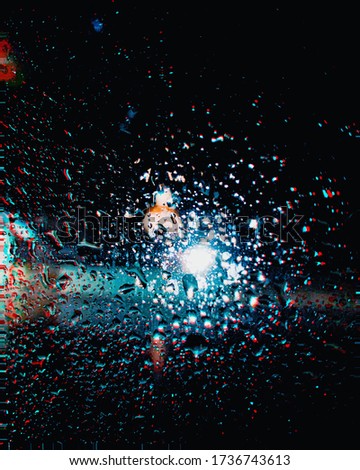 Nighttime moody picture of raindrops on car window. Psychedelic edit.