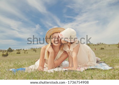 Young mother and her daughter having fun in nature park, girl kissing her mother