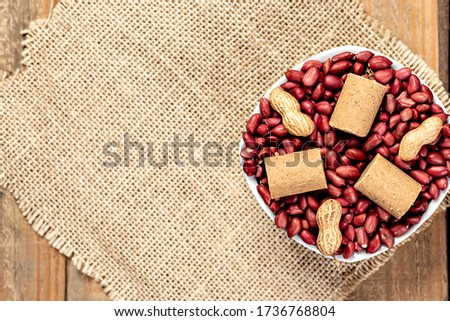 raw red peanuts and peanuts in the shell inside a white crockery on top of a burlap cloth - Typical sweets from the Brazilian June party - Top view with copy space