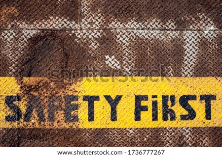 "safety first" sign painted on a rough, rusty checker plate