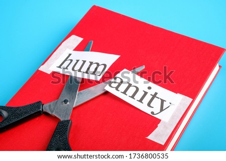 the word humanity is cut with scissors on a red book. humanity is over she is not needed
