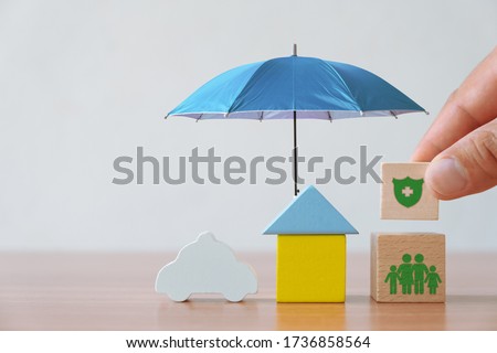 Insurance and investment concept of health, life, accident and travel. Hand picked wooden block with insurance sign and symbol of house, family, car