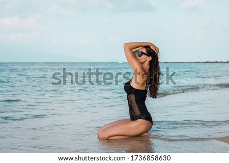 Portrait of caucasian woman in black swimsuit on beach