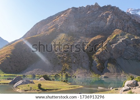 The Pamir range view and peaceful campsite on Kulikalon lake in Fann mountains in Tajikistan. Amasing colorful reflection in pure ice lake.