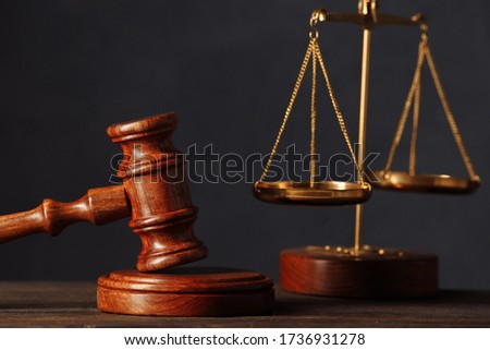 Law and justice concept. Lawyers desk. Judge's gavel close-up, scales, wooden table. Dark gray bokeh background