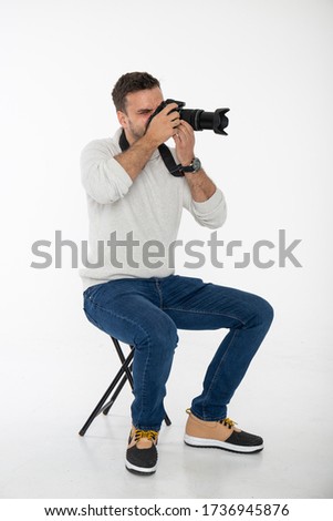 Photographer looking through the lens in studio. Isolated on white background.