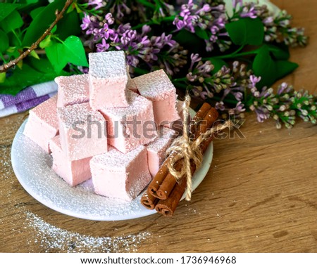 
pink pastille on a white plate with flowers and cinnamon