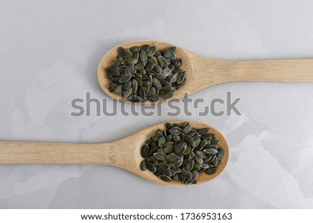 Peeled pumpkin seeds in a wooden spoon on a light vintage background. Natural food. Suitable for background. Vegan.