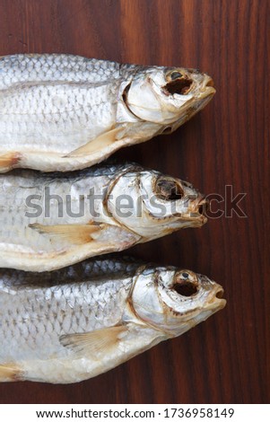 detailed close up top view shot of three Russian dried salted vobla (Caspian Roach) fish on a dark wooden plate background