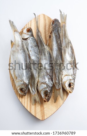 vertical close up top view shot of a bunch of five Russian dried salted vobla (Caspian Roach) fish on a wooden plate on a white background