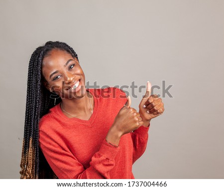 Happy, positive African American female in red color shirt on gray background. Copy Space