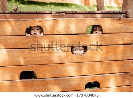 three sisters are playing in the Playground and peeking through 