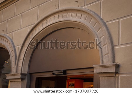 Building with a showcase. Empty plate in the form of an arch on an old house. Empty space for a number, text or store name on glass. Side view from below. Black metal minimal design for advertising.