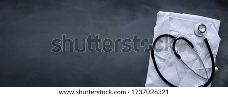 Stethoscope and doctor cloth over chalkboard, medical concept