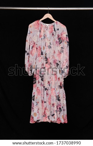 Woman fashion long floral pattern dress on hanging-black background

