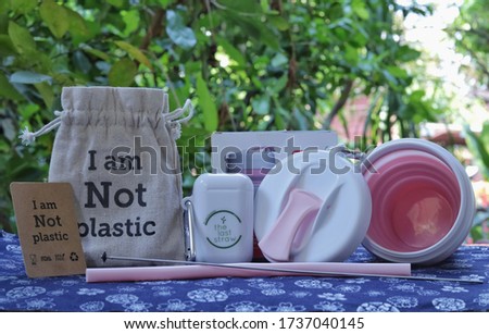 Pink cup, pink Straw, calico bag and cleaning stainless pick put on blue and flower vintage fabric. Word in the photo is I am Not Plastic, The last straw and by I am not Plastic. - Save world concept.